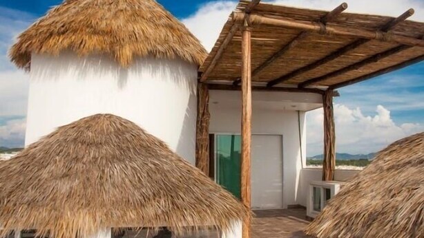 Un bâtiment doté de toits en chaume et d’une pergola en bois.