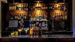 A bar area with multiple shelves of liquor bottles, a coffee machine, and a variety of drinks on the counter. - Magna Hotel and Suites (Nairobi)