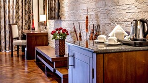 A modern kitchen with a stone wall, wooden counter, and a vase with red flowers. - Magna Hotel and Suites (Nairobi)
