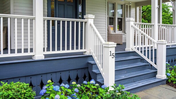 A two-story house with a porch, white railings, and a blue door. - Station Inn Pawling (Pawling)