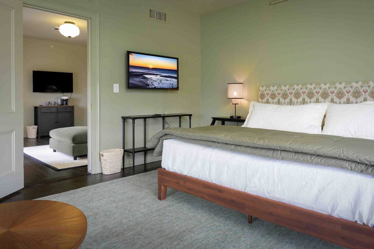 A bedroom with a bed, a TV, a lamp, and a view of the ocean.