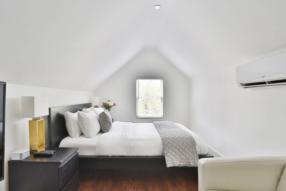 A bedroom with a bed, bedside table, lamp, and a window.