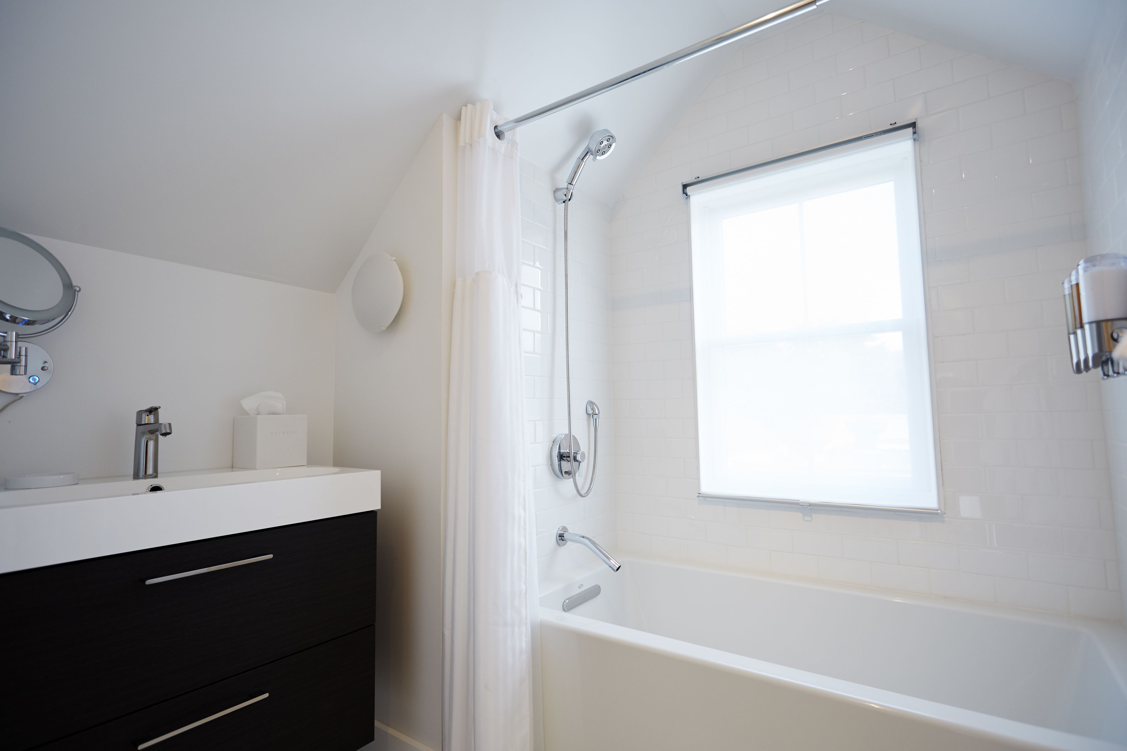 A modern bathroom with a white vanity, a bathtub, and a shower.