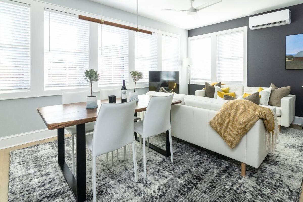A modern living room with a white sofa, a dining table, and a TV.