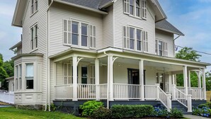 A two-story house with a wrap-around porch, multiple windows with shutters, and a steeply pitched roof. - Station Inn Pawling (Pawling)