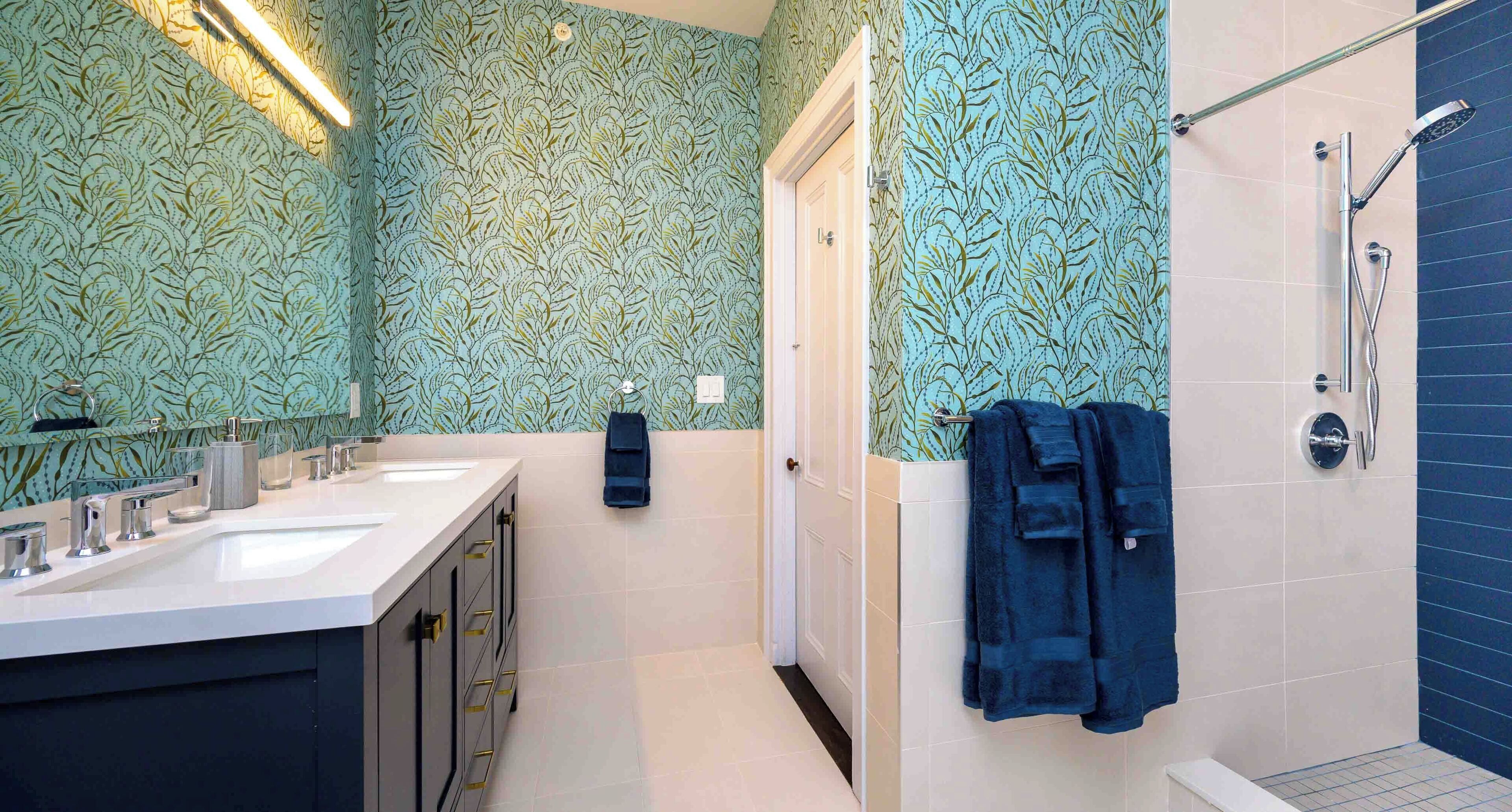 A bathroom with two sinks, a shower, and a door leading to another room.