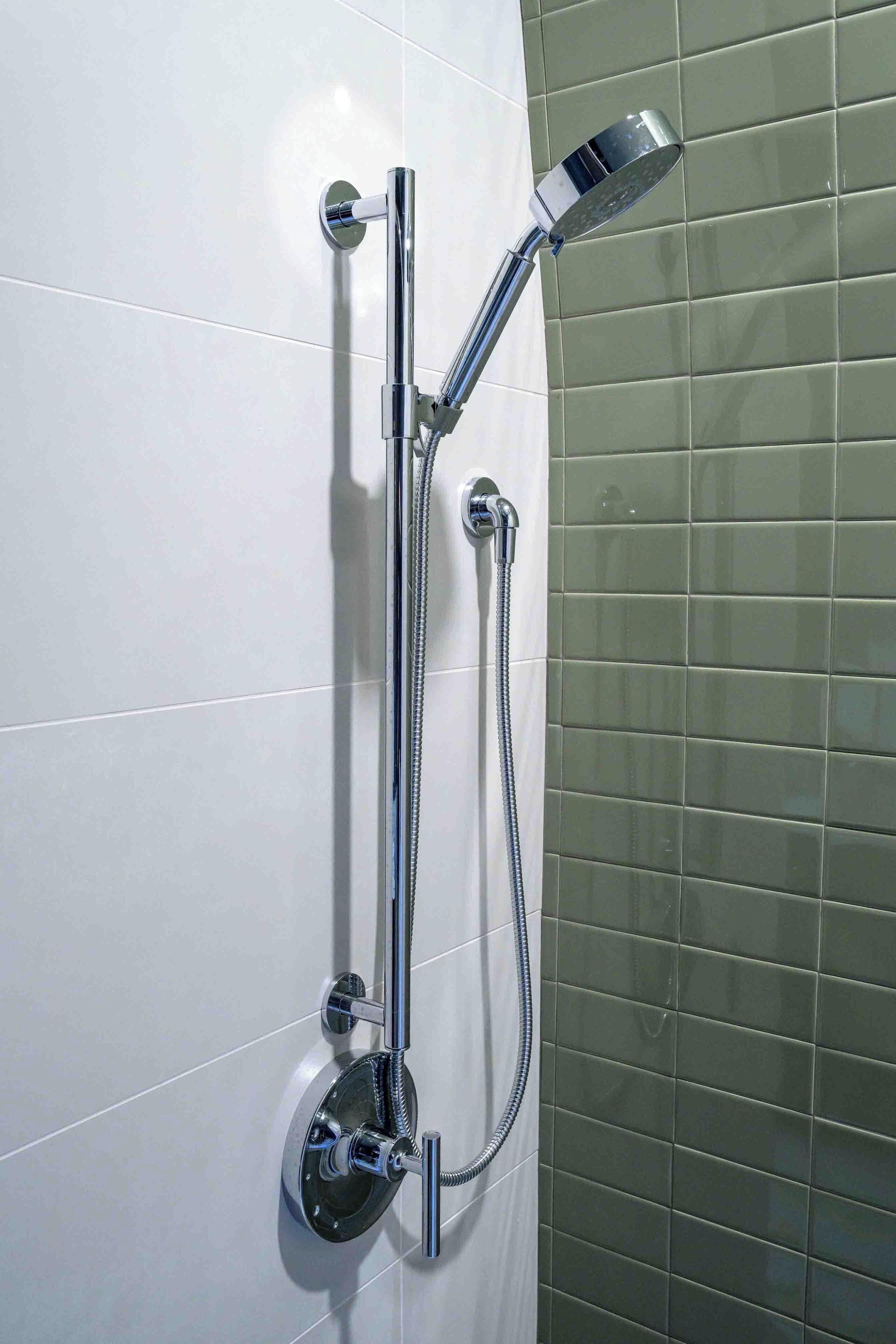A wall-mounted shower with a handheld showerhead and a fixed showerhead, both with chrome finishes.
