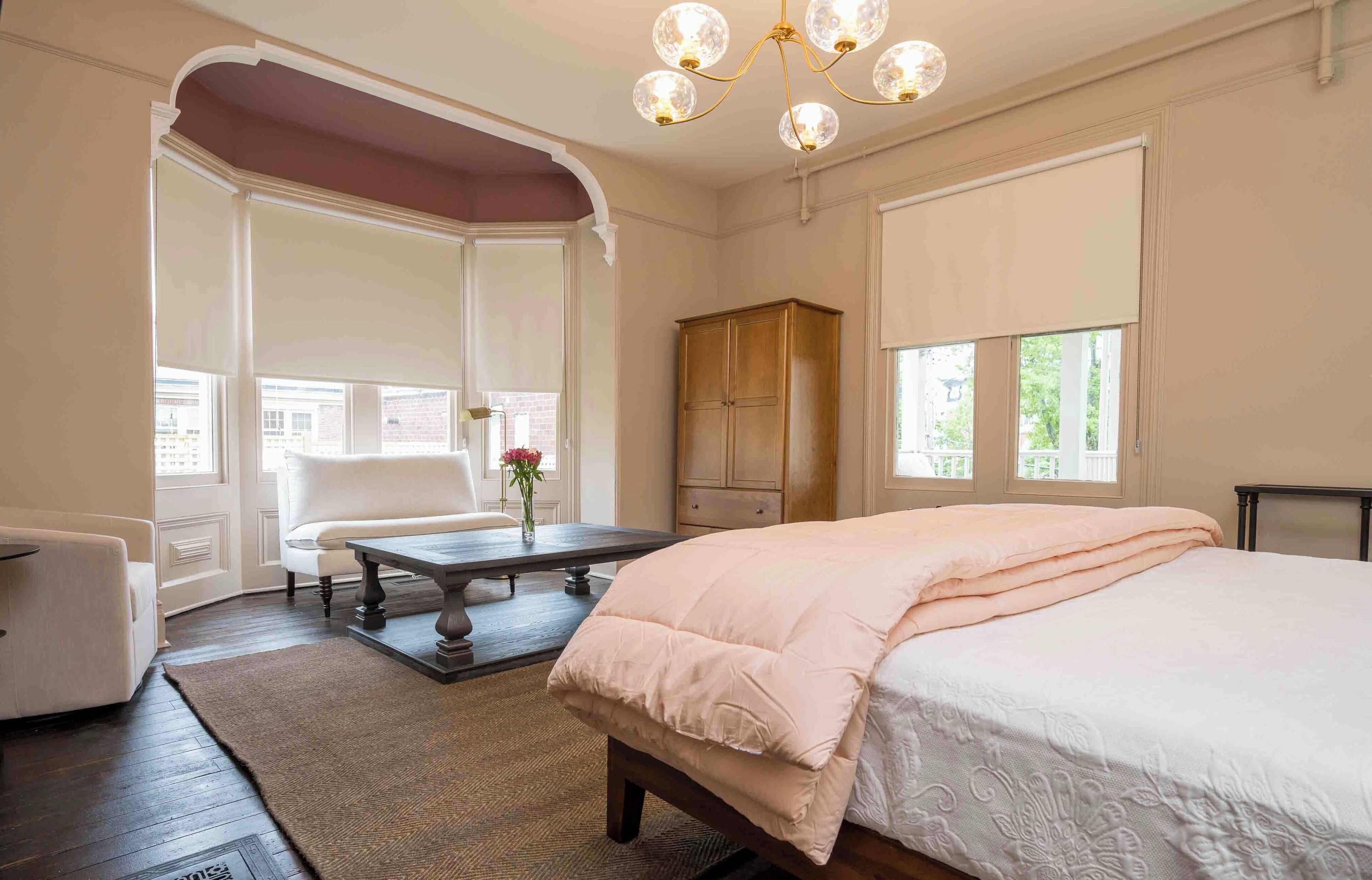 A bedroom with a large bed, a wooden cabinet, a desk, and a chair.