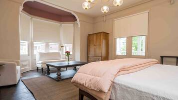 A bedroom with a large bed, a wooden cabinet, a desk, and a chair.