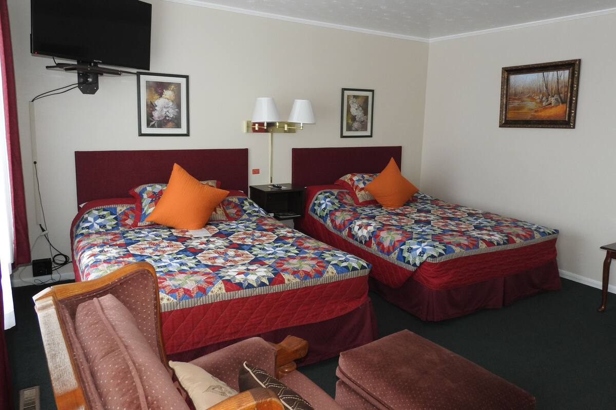 A hotel room with two beds, a TV, a desk, and a chair.