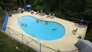 A swimming pool with a deck area, lounge chairs, and a fence.