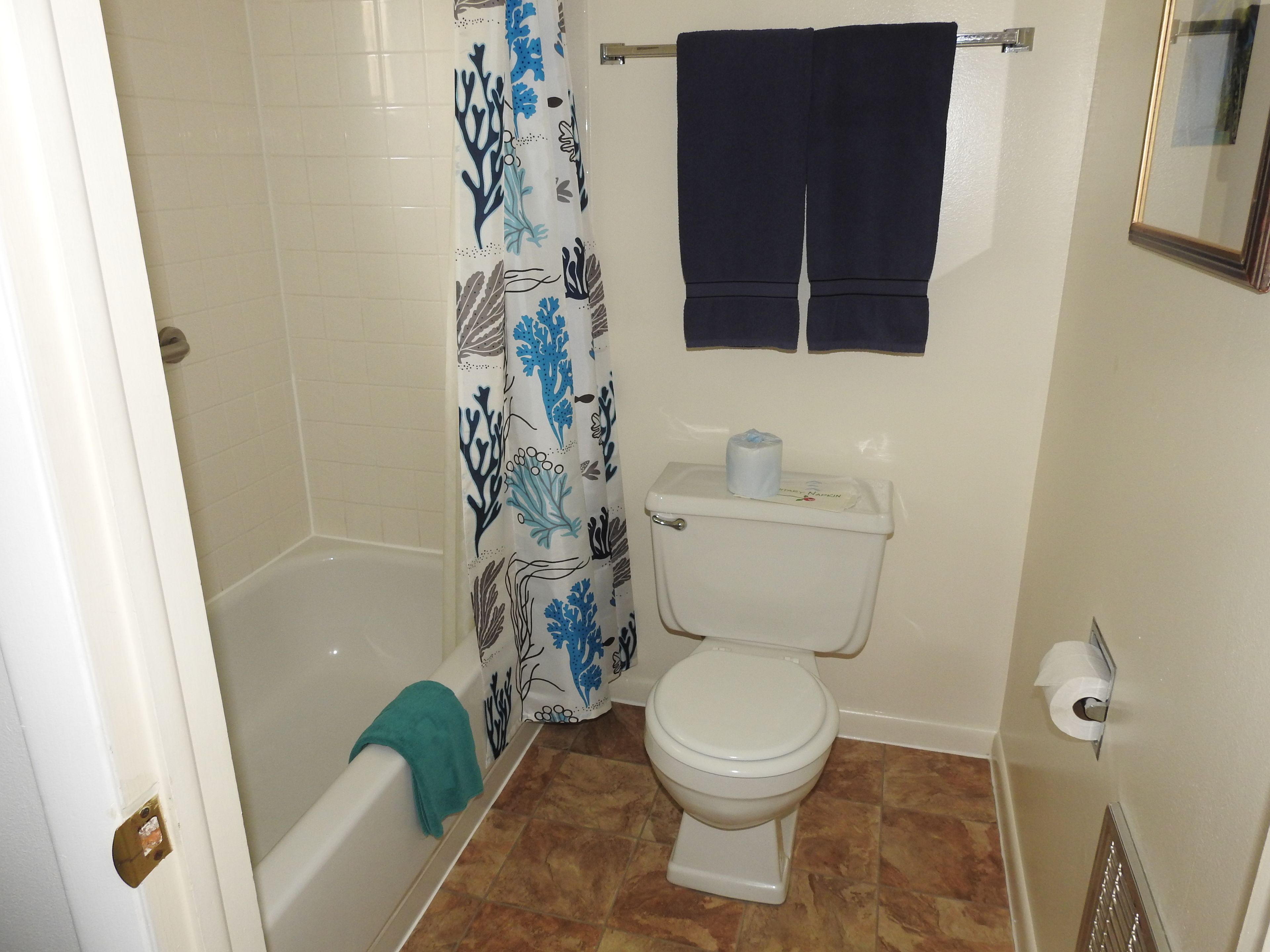 A bathroom with a bathtub, toilet, and shower curtain.