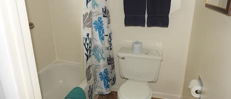 A bathroom with a bathtub, toilet, and shower curtain.