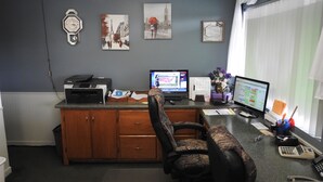 A home office with a desk, computer, printer, and a chair.