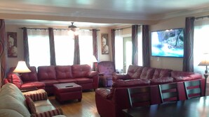A living room with a red sofa, a white armchair, a wooden coffee table, and a dining table. - JARVIS Edgewater Park & Beach 5BD Villa (Cleveland)