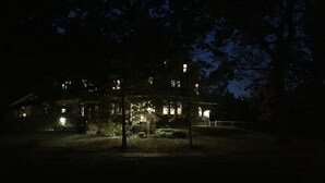 A large, multi-story building with illuminated windows at night, surrounded by trees. - JARVIS Edgewater Park & Beach 5BD Villa (Cleveland)
