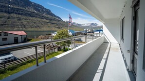 Een balkon met uitzicht op een berg, een vlag en een gebouw met een rood dak.