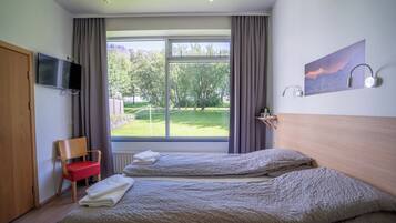 Habitación de hotel con dos camas, un televisor, un cuadro y vistas a un paisaje verde.