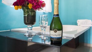 Une bouteille de champagne Valdivieso Brut, un verre et un vase de fleurs posés sur une surface réfléchissante.