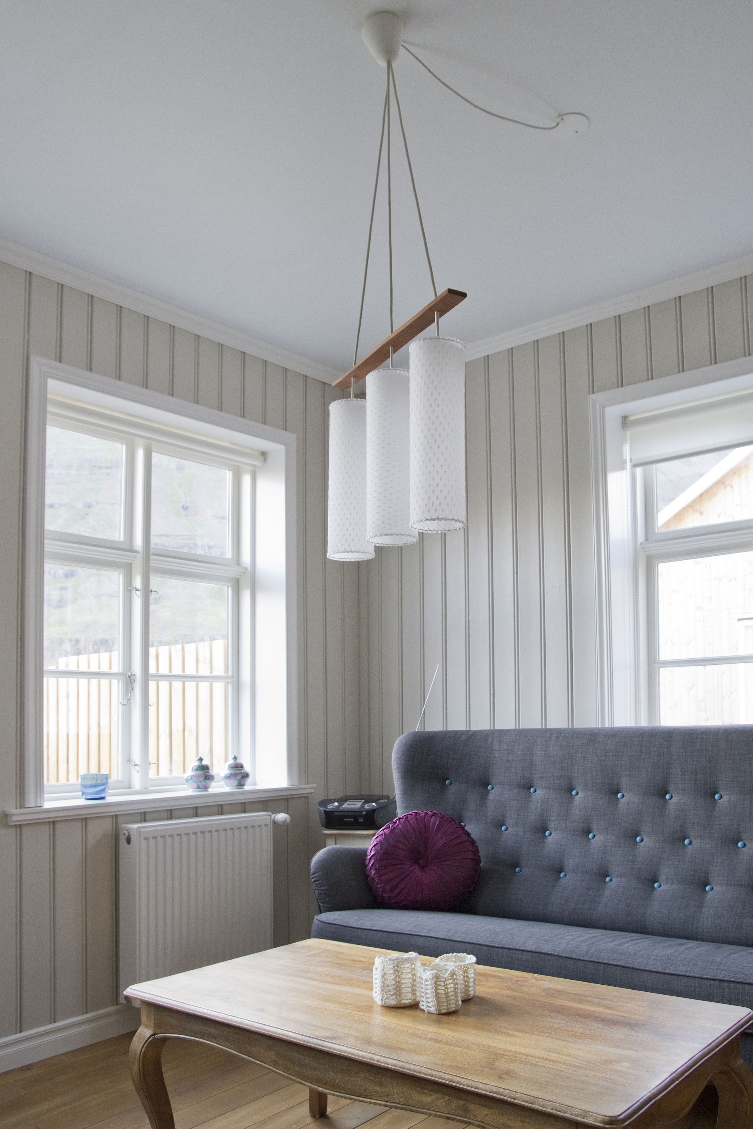A room with a grey sofa, a wooden coffee table, and a hanging light fixture.