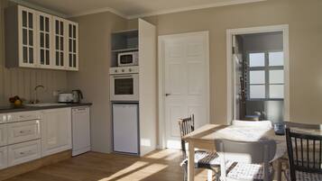 A kitchen with white cabinets, a microwave, a dishwasher, and a dining area with a table and chairs.