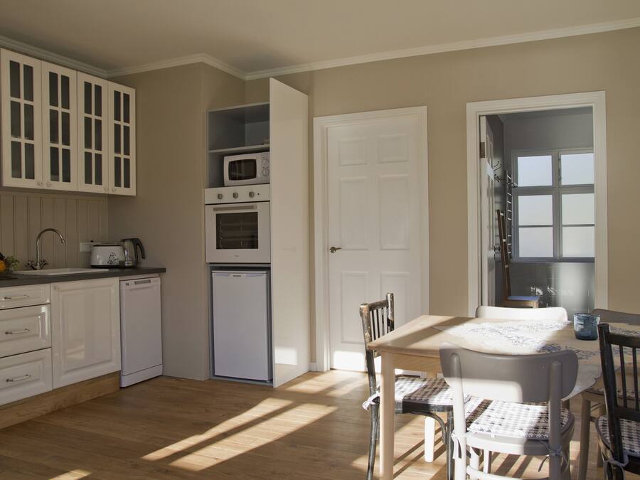 A kitchen with white cabinets, a microwave, a dishwasher, and a dining area with a table and chairs.