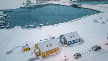 An aerial view of a snow-covered area with buildings, a frozen lake, and a person walking.