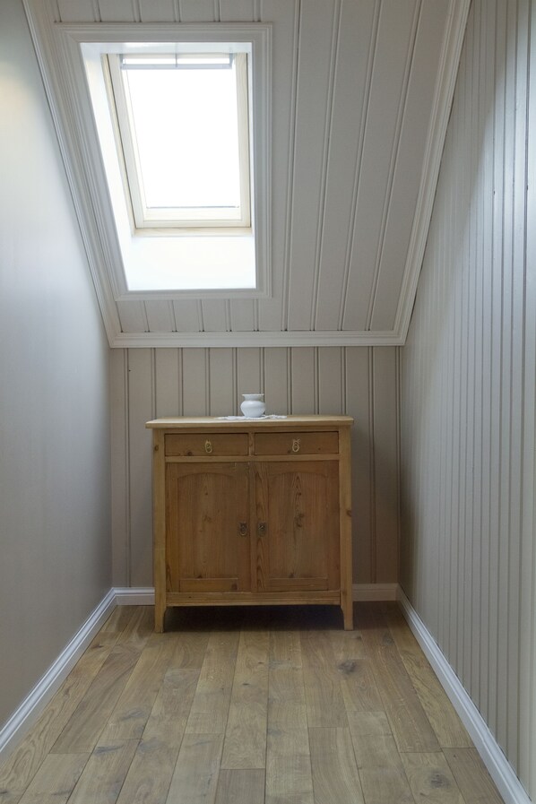 A room with a sloped ceiling, a wooden cabinet, and a skylight.