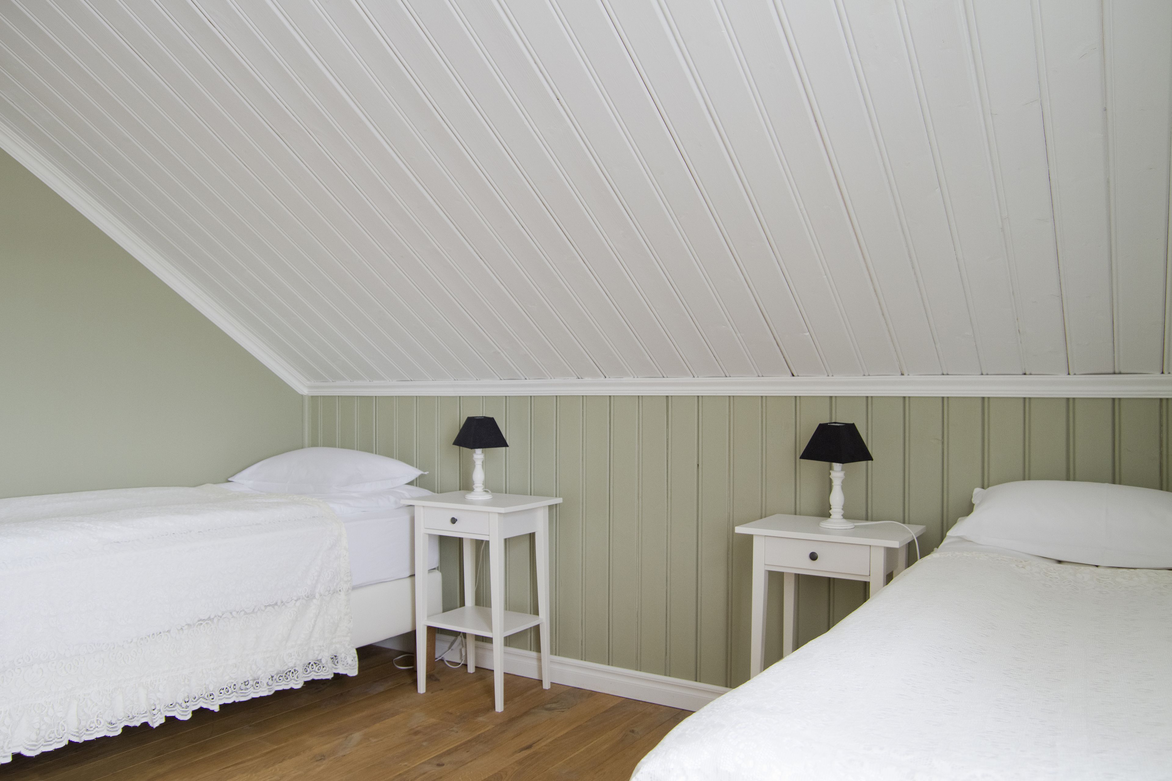 A bedroom with two single beds, a sloped ceiling, and two bedside tables with lamps.