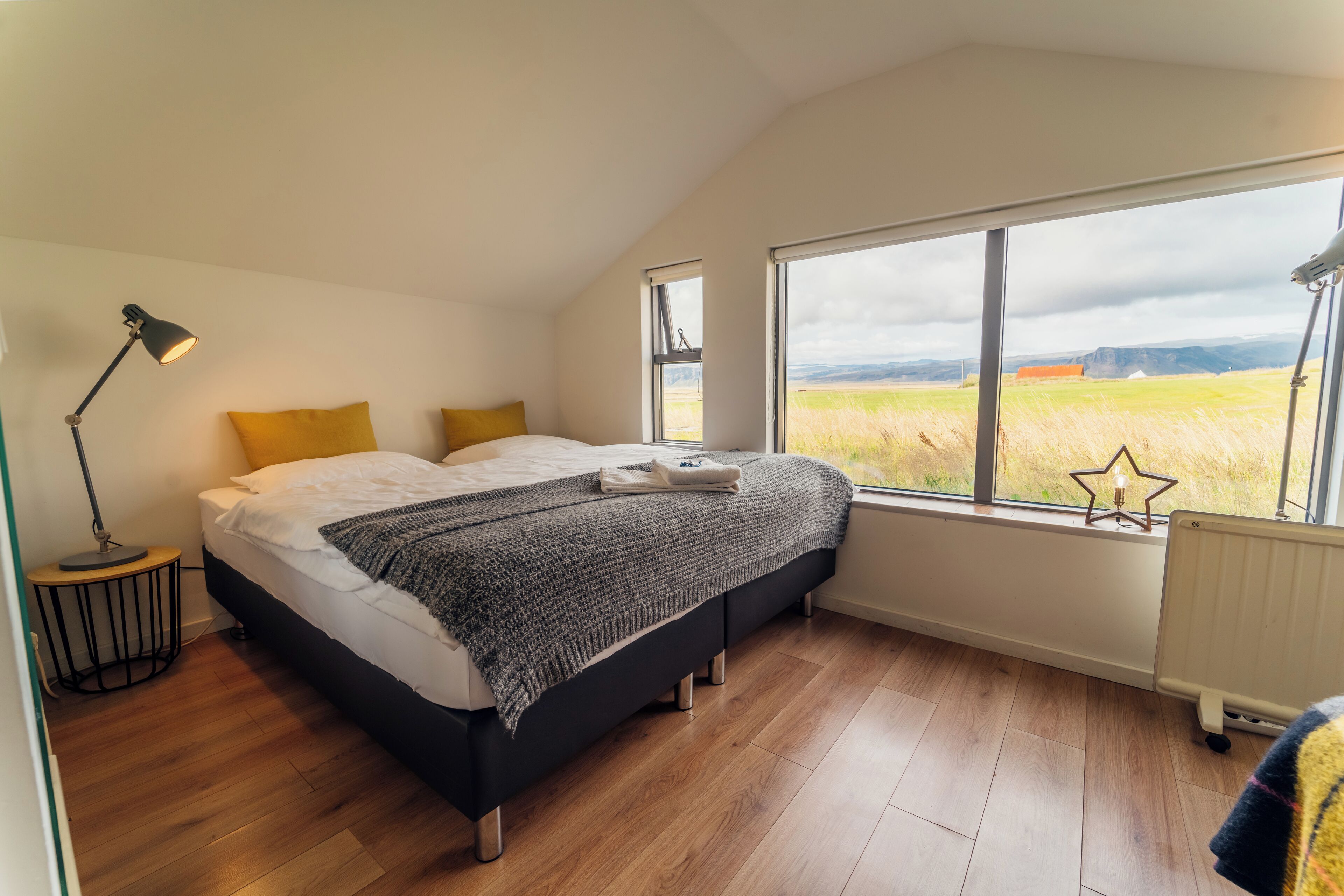 Un dormitorio con cama, lámpara, ventana decorada con una estrella y vista a un campo.