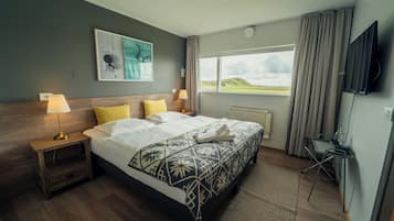 Ein Hotelzimmer mit Bett, Schreibtisch, Fernseher, Fenster mit Blick und einem Gemälde an der Wand.