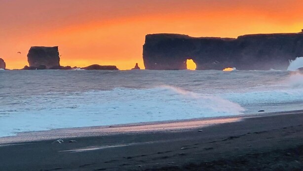 A beach with large rock formations and waves crashing onto the shore.