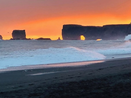 A beach with large rock formations and waves crashing onto the shore.