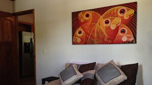 Ein Schlafzimmer mit einem Bett, Kissen, einem Gemälde und einer Tür zu einem anderen Raum.