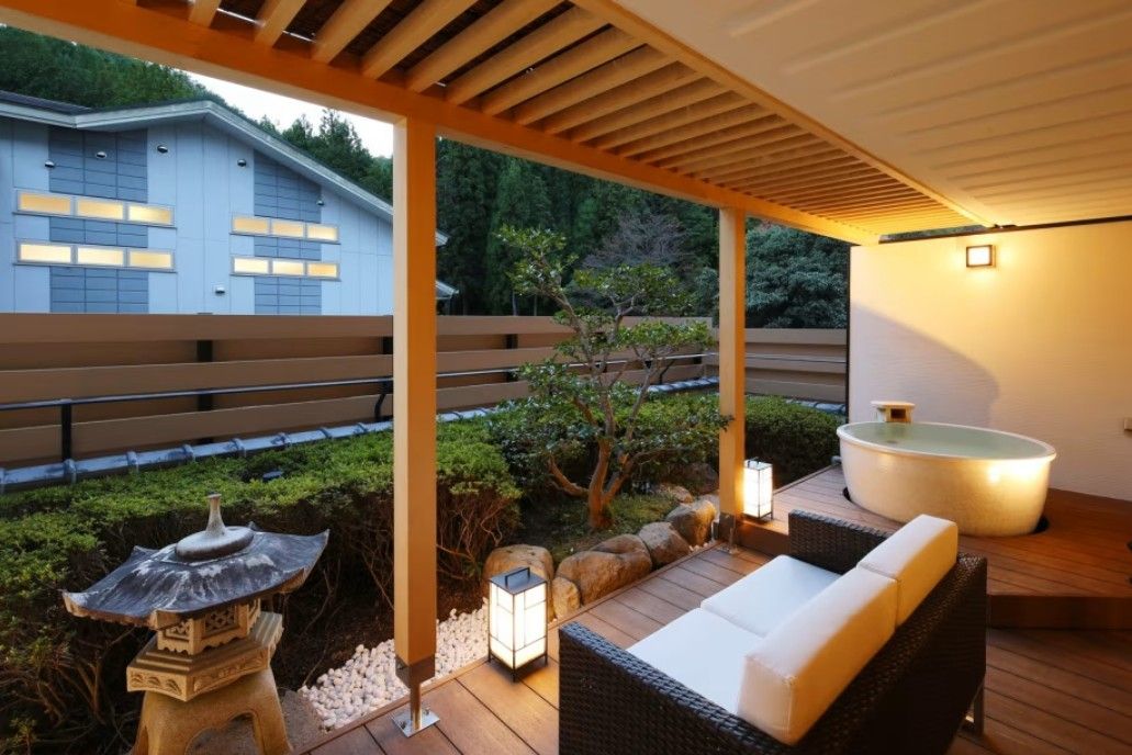 Un espace extérieur aménagé, abrité et doté d’un jacuzzi, de lanternes en pierre et d’une pergola en bois.