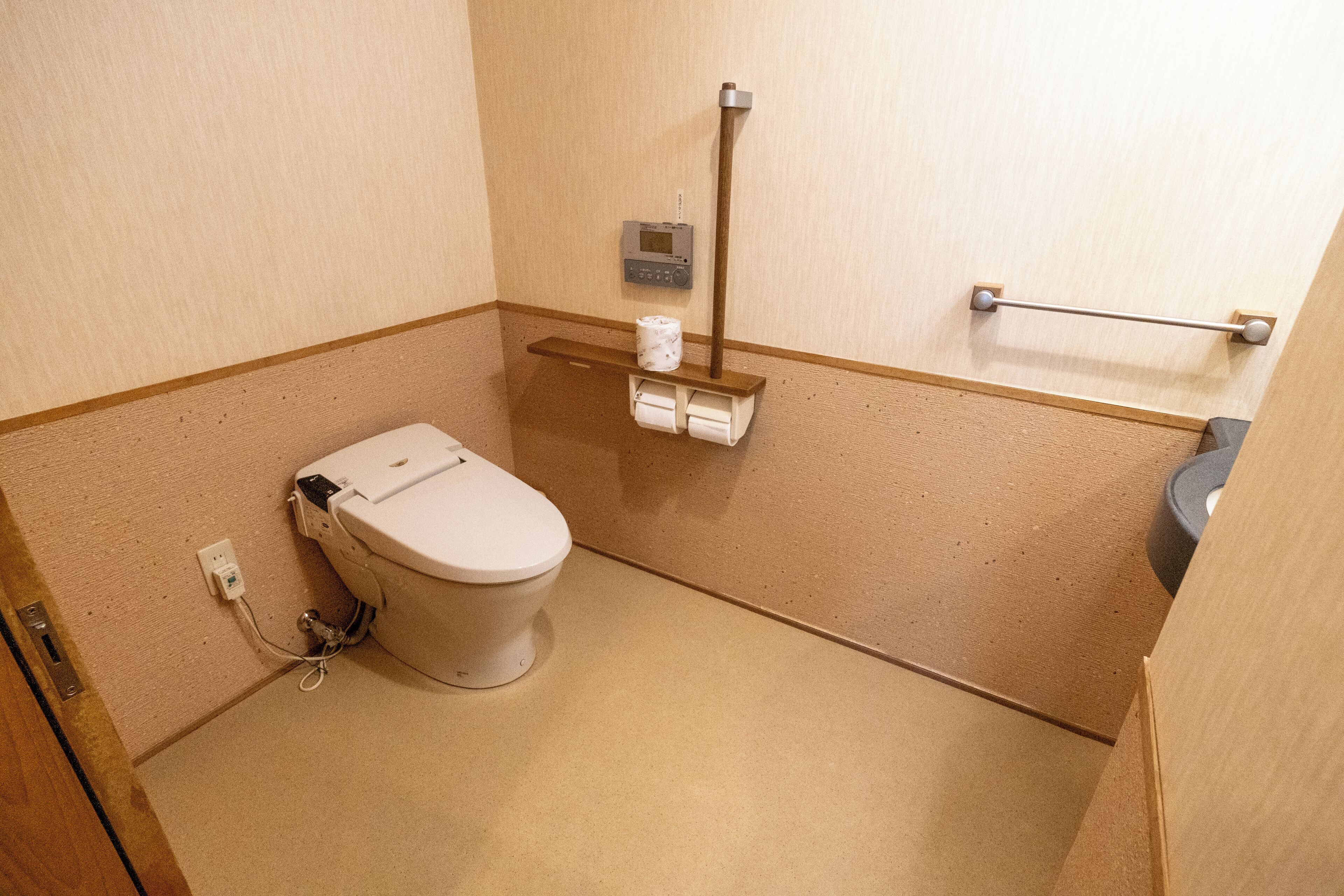 Une petite salle de bain compacte, équipée de toilettes, d’un sèche-mains et d’un distributeur de serviettes en papier.