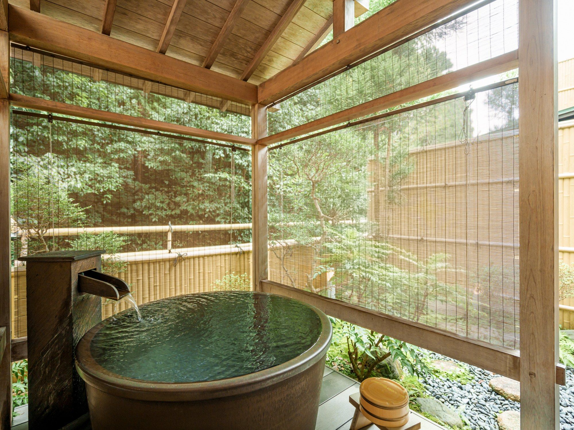 A hot tub with a wooden structure and a view of a garden through a screened window.