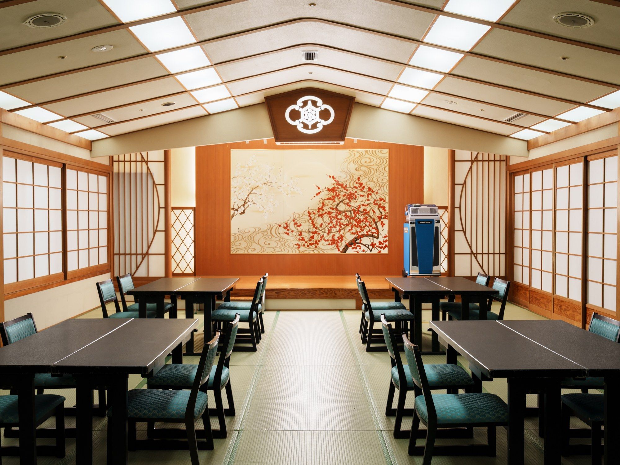 A conference room with tables and chairs, a large decorative wall, and a ceiling with recessed lighting.