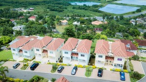 Un quartier résidentiel où les maisons sont dotées de toits recouverts de tuiles rouges et où se trouve un parking avec plusieurs voitures.