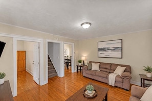 A living room with a sofa, a coffee table, and a painting on the wall.