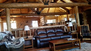 A rustic log cabin interior with a leather sofa, wooden coffee table, and a patterned armchair. - Authentic Hand-Crafted Mountain Cabin w/ Amazing Lake View ! (Somers)