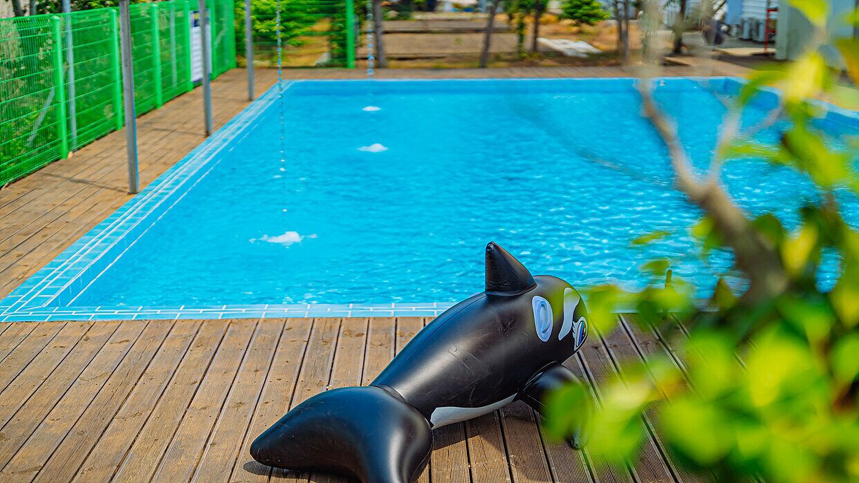 A pool with a wooden deck and a lifebuoy.