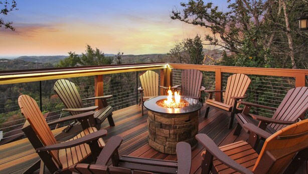 Eine Terrasse mit Adirondack-Stühlen und einem Steinkamin.