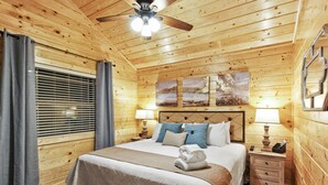 Ein Schlafzimmer mit Holzvertäfelung, einem Bett, zwei Nachttischlampen, einem Nachttisch und einem Deckenventilator.