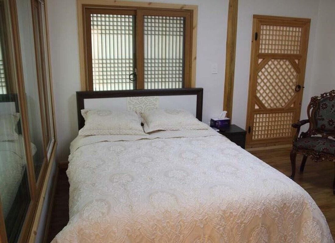 Een slaapkamer met een bed, een houten deur en een stoel.