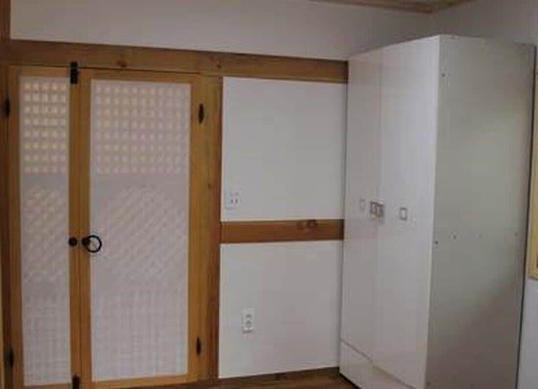 A room with a wooden door, a white wardrobe, and a white cabinet.