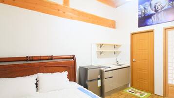 A bedroom with a wooden bed, a small kitchenette, and a door.