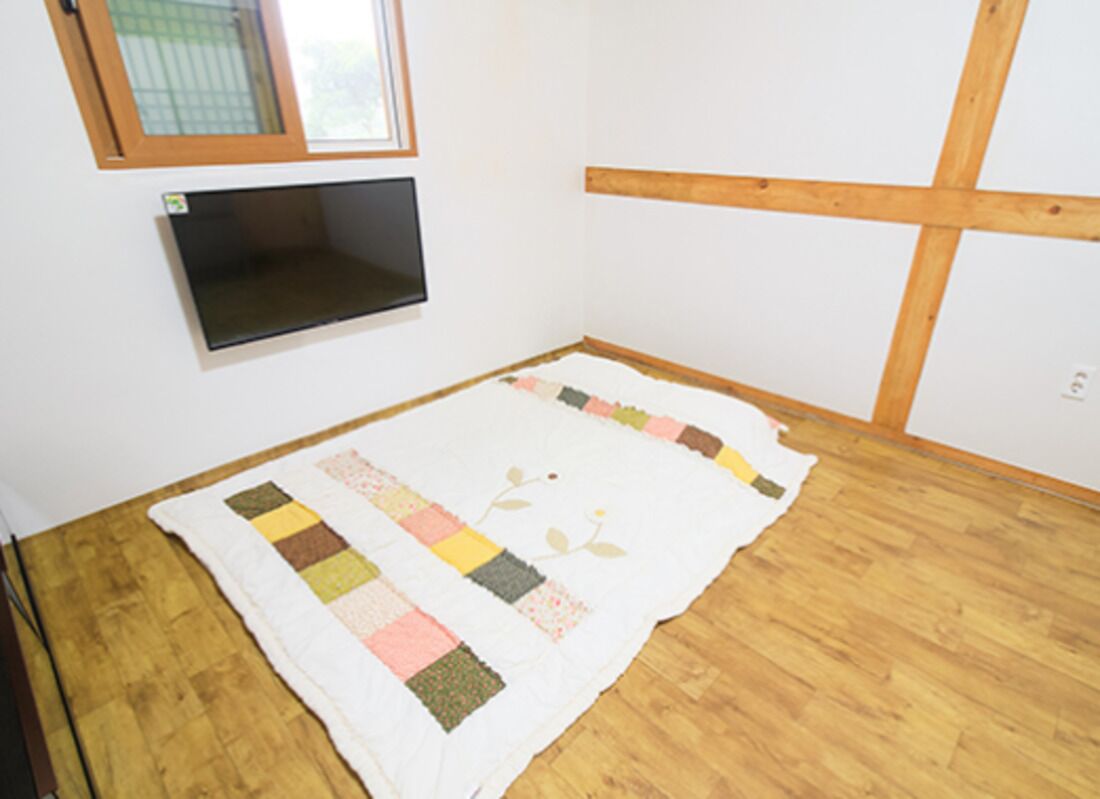 Una habitación con suelo de madera, pared blanca y estructura de vigas de madera.