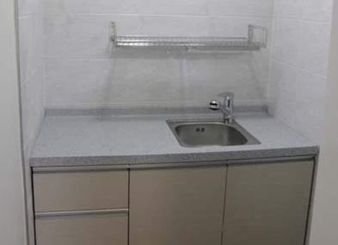 Una cocina pequeña con un lavamanos, una encimera y armarios.