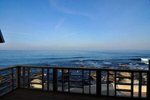 Una terrazza in legno con vista sulla costa rocciosa e l'oceano.